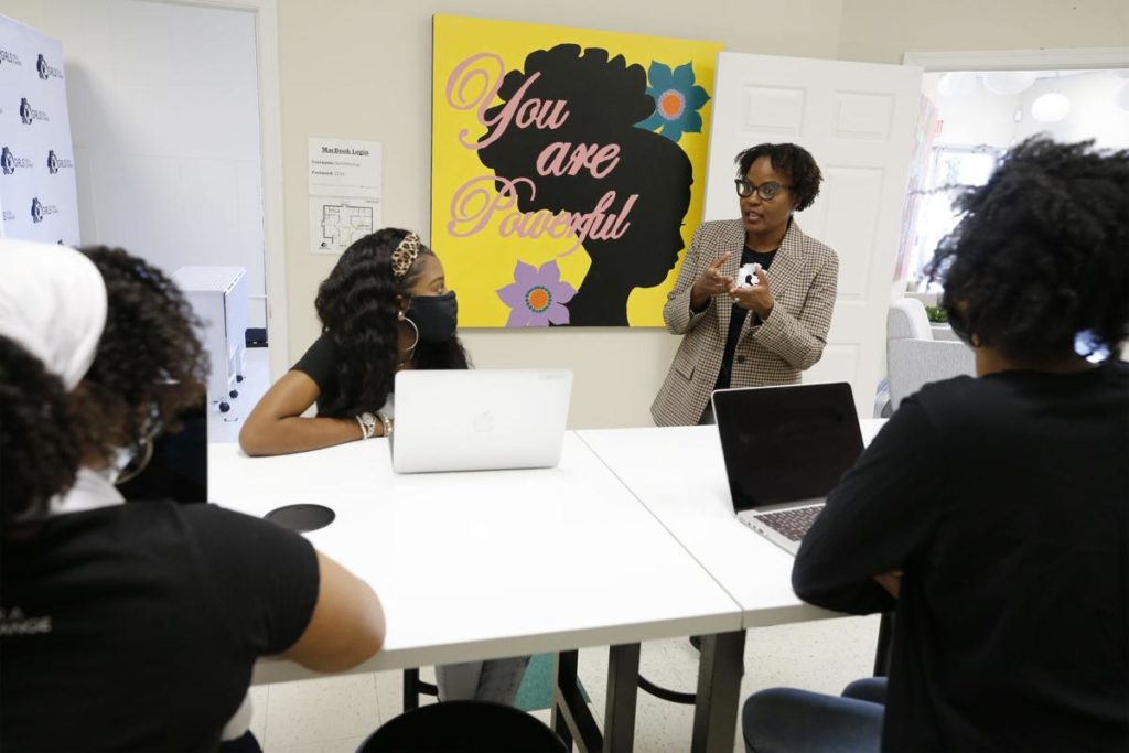 Smiling Black woman speaking to two Black girls in a technology lab