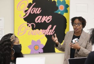 Smiling Black woman speaking to two Black girls