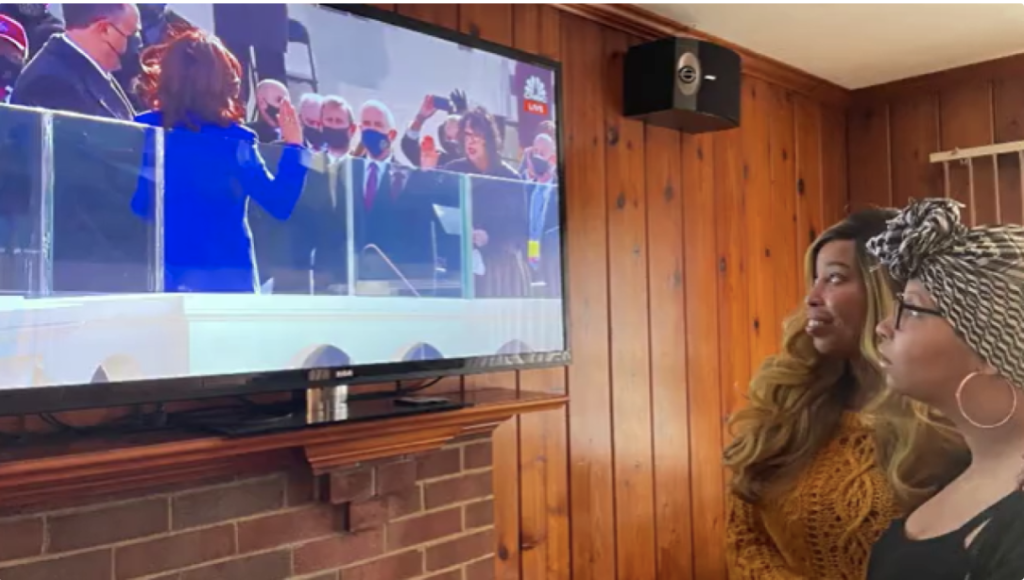 Black women watching as Vice President Harris is sworn in on television