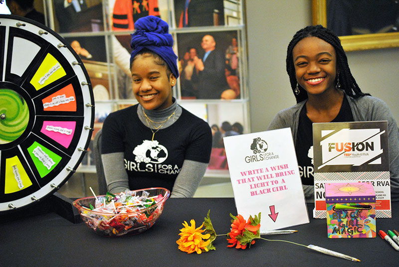 girls-for-a-change-black-girl-rally Happy Black girls sitting at a vendor table together